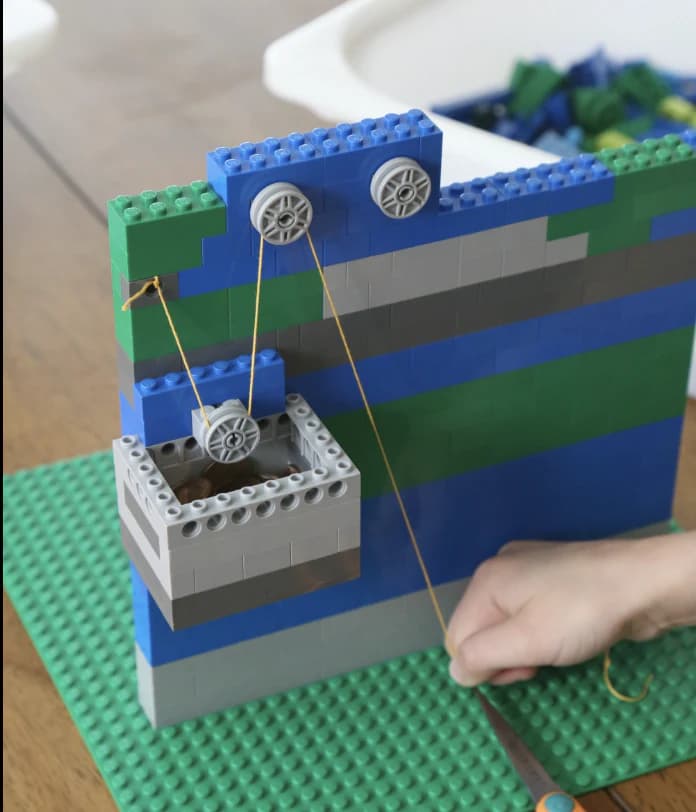 Brick-built pulley elevator with a suspended car, rope path, supporting wall, and free pull cord.